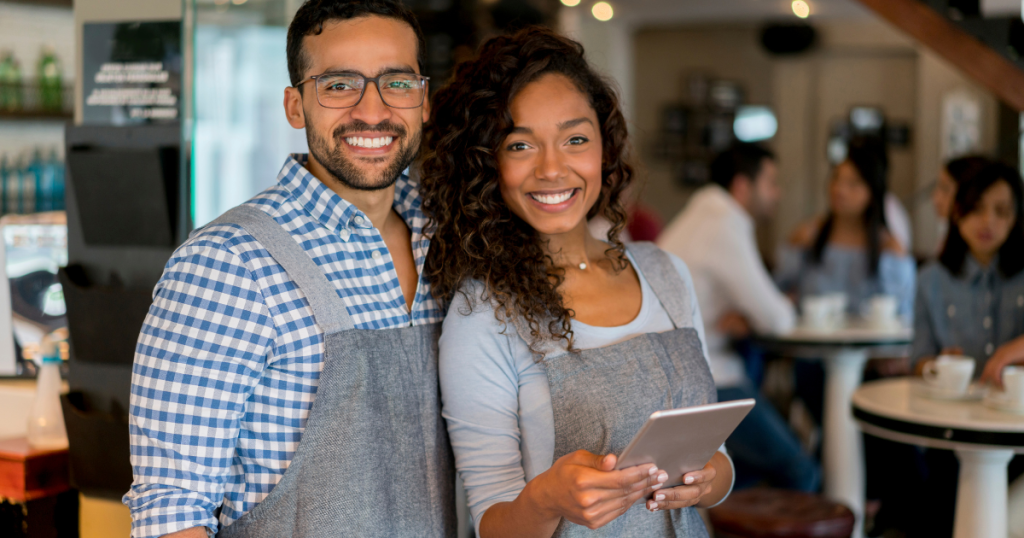 Smiling business owners in a cafe, showcasing flexible business line of credit for finished merchandise financing.