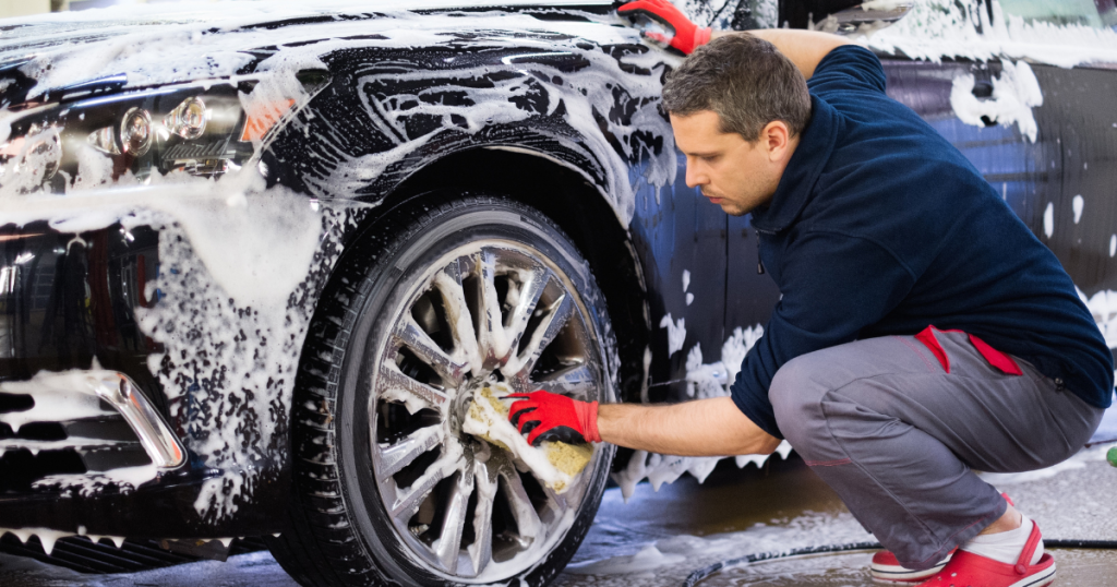 Car wash employee cleaning a vehicle, showcasing the importance of funding for business growth and equipment upgrades.