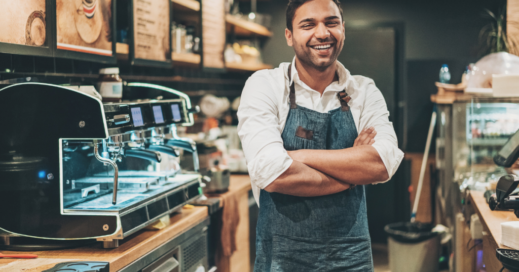 Smiling barista in a coffee shop, showcasing business growth and credit card receivable financing opportunities.