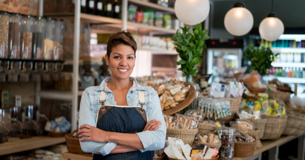 Smiling business owner in a retail store showcasing products, representing unsecured loans for business growth and sustainability.