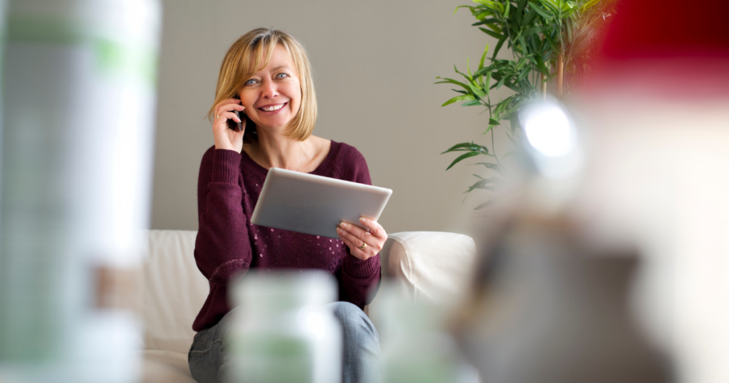 Smiling woman on the phone with a tablet, exploring unsecured business loans for real estate potential.