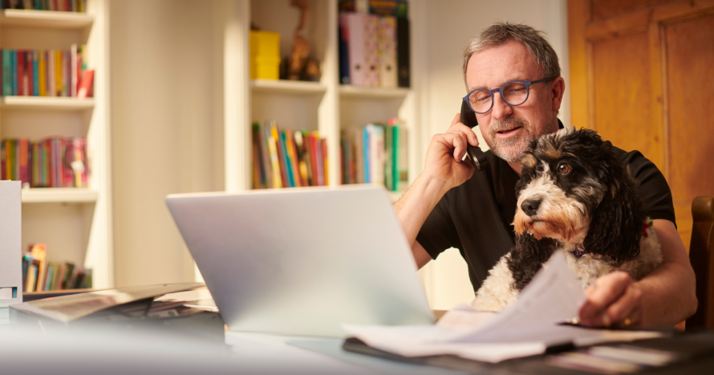 Man on phone with dog, working on real estate investment strategies using unsecured business loans for growth.