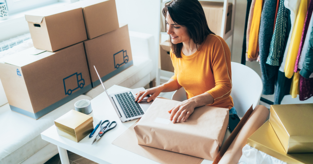 Woman managing her small business finances with packages and laptop, highlighting unsecured business loan eligibility.