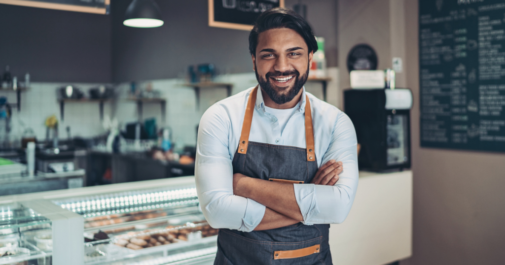 Smiling business owner in a cafe, showcasing the benefits of invoice factoring for small businesses.