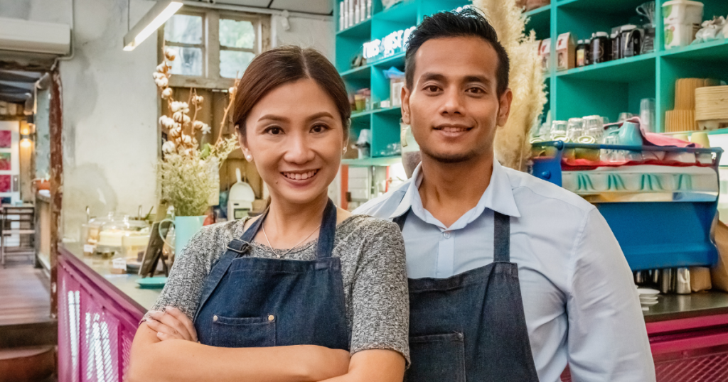 Business owners smiling in a cafe, representing growth through purchase order funding and financial solutions.