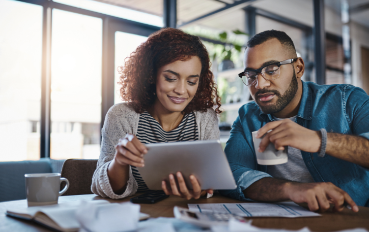 Couple reviewing financial information on a tablet, exploring new credit opportunities and FICO score improvements.