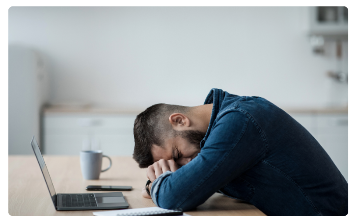 Stressed businessman with head down on desk, highlighting the challenges of the business loan application process.