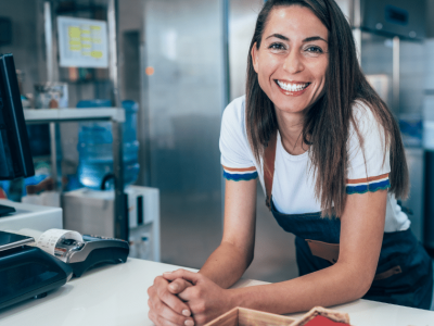 Smiling business owner at a counter, representing innovative equipment leasing and finance for business growth.