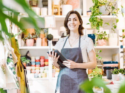 Smiling business owner in a plant shop, showcasing flexible financing options for small businesses.