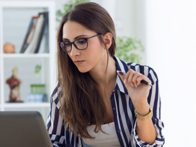 Businesswoman analyzing strategies for success while working on a laptop in a modern office setting.