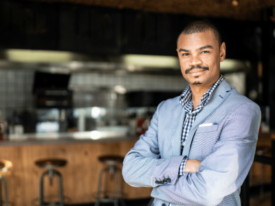Business owner in a suit standing confidently in a modern cafe, representing growth through Merchant Advance Loans.