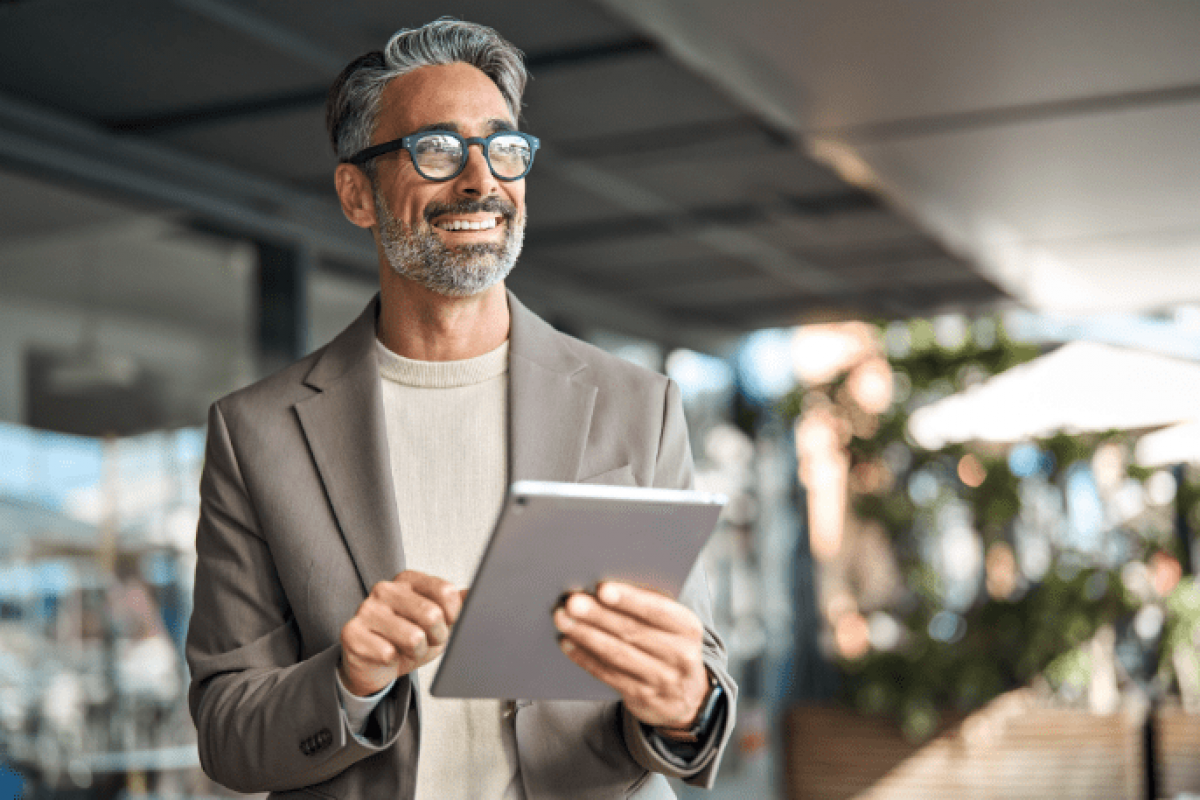 Smiling professional man using a tablet, representing employee empowerment and business growth strategies.