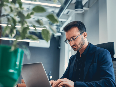 Professional man working on a laptop in a modern office, emphasizing employee engagement strategies in business.