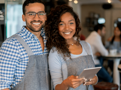Smiling business owners in a cafe, showcasing flexible business line of credit for finished merchandise financing.