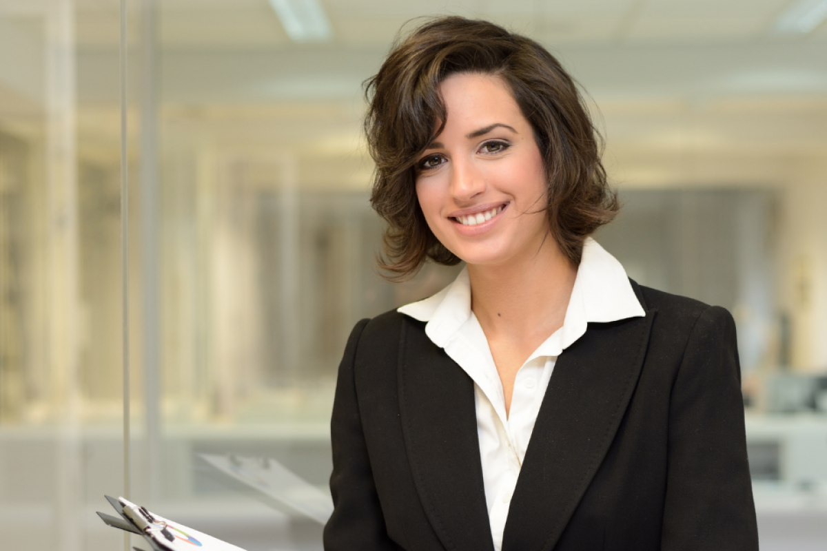 Professional woman in business attire smiling, representing strategic business loans and financial growth opportunities.