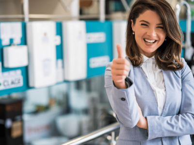 Smiling businesswoman giving a thumbs up in a retail environment, representing small business success and unsecured credit lines.