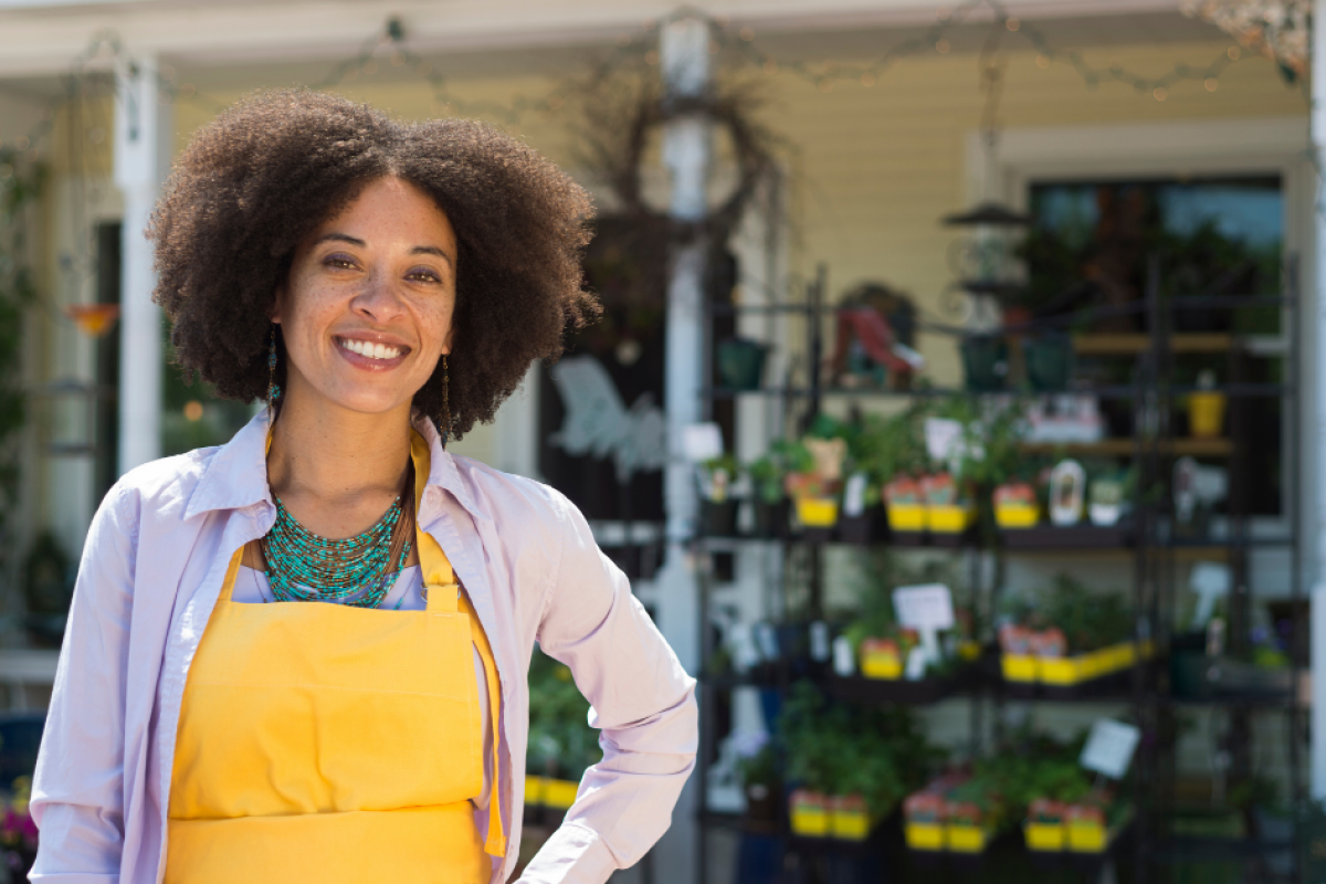 Smiling business owner in an apron outside a plant shop, representing bad credit loans for small business growth.