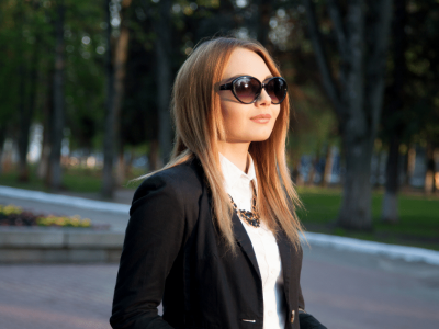 Business professional in sunglasses, exuding confidence and style in a park setting, representing success strategies.