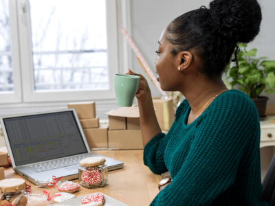 Business owner analyzing growth strategies with Johari's Window model, coffee in hand, surrounded by packages and a laptop.