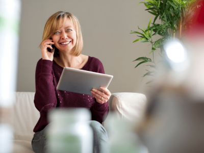 Smiling woman on the phone with a tablet, exploring unsecured business loans for real estate potential.