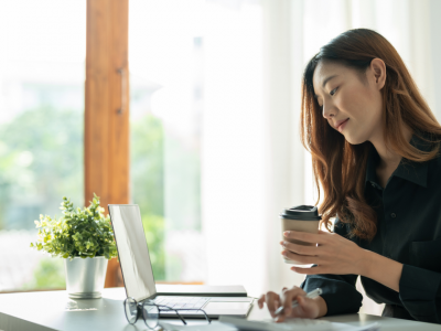 Woman working on a laptop with a coffee cup, exploring flexible business loan options for bad credit.