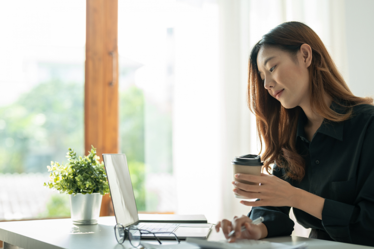 Woman working on a laptop with a coffee cup, exploring flexible business loan options for bad credit.