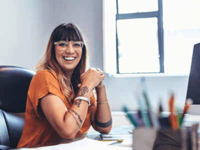 Smiling woman in an office discussing self-employment tax impacts on LLC owners and business financing solutions.