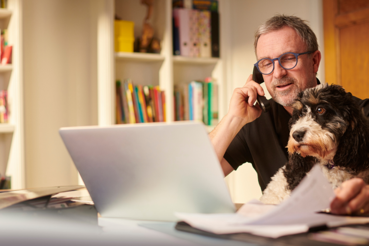 Man on phone with dog, working on real estate investment strategies using unsecured business loans for growth.