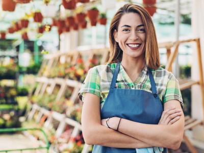 Smiling woman in an apron at a garden center, representing customer service and business growth strategies.