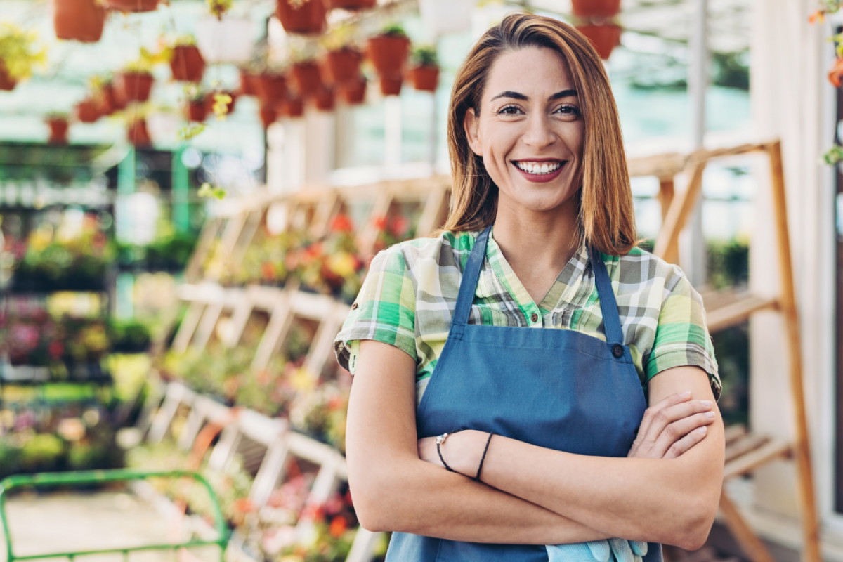 Smiling woman in an apron at a garden center, representing customer service and business growth strategies.