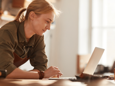Woman working on a laptop in a workshop, exploring unsecured business loans and credit options for small businesses.
