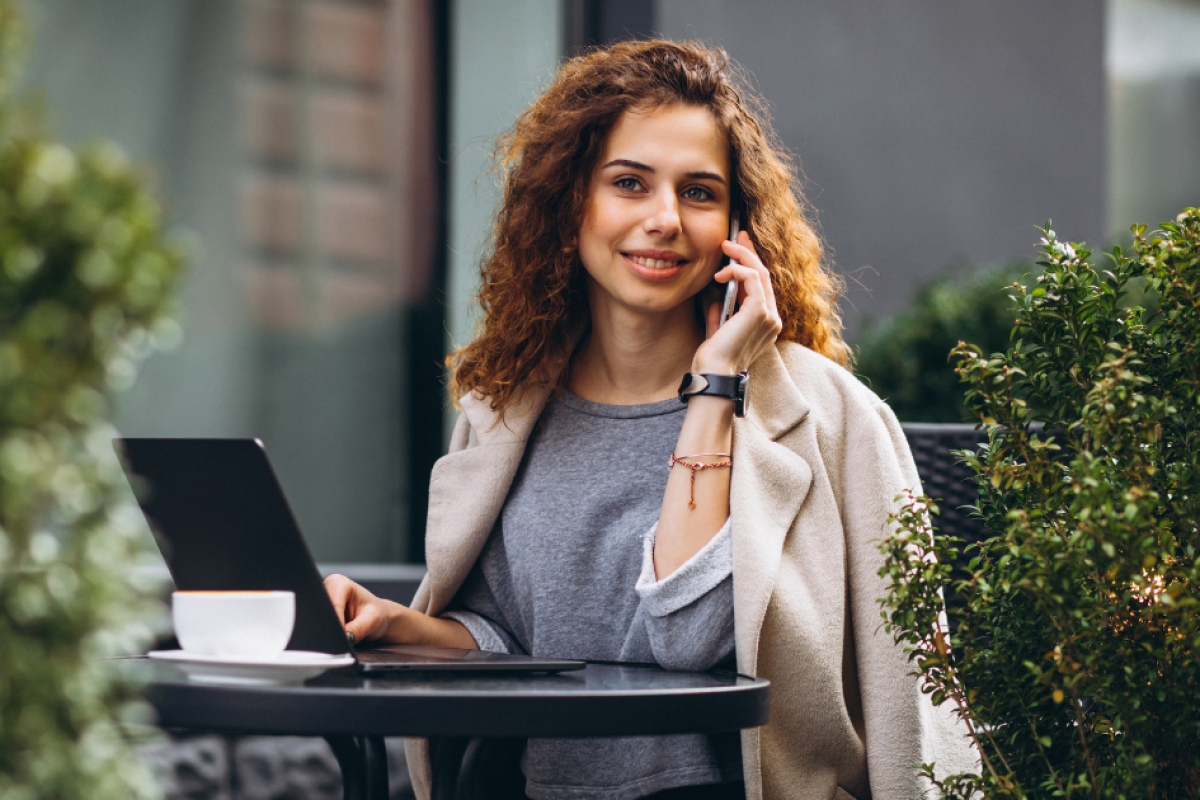 Young woman on a phone at a laptop, representing strategic blogging and dynamic content for SEO improvement.