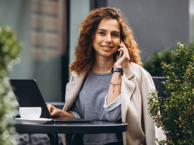 Young woman on a phone at a laptop, representing strategic blogging and dynamic content for SEO improvement.