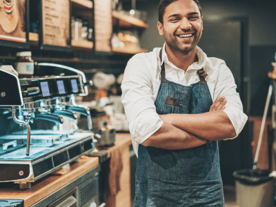 Smiling barista in a coffee shop, showcasing business growth and credit card receivable financing opportunities.