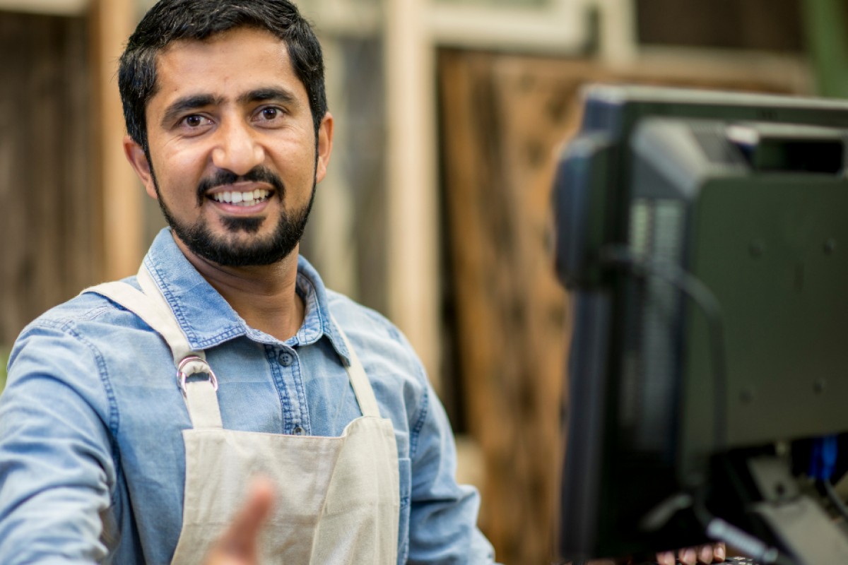 Smiling small business owner at a computer, representing small business financing and growth opportunities.