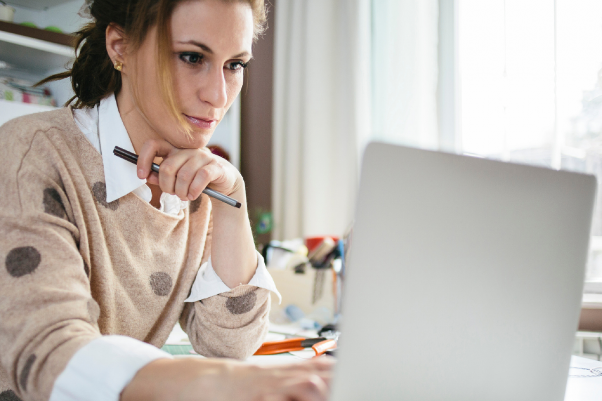 Woman working on a laptop, focused on achieving professional greatness and sustainable success strategies.