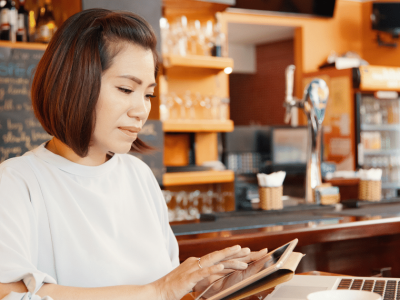 Woman using mobile payment solutions in a cafe, showcasing the convenience of digital transactions for businesses.