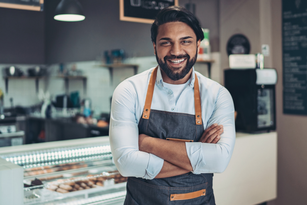 Smiling business owner in a cafe, showcasing the benefits of invoice factoring for small businesses.