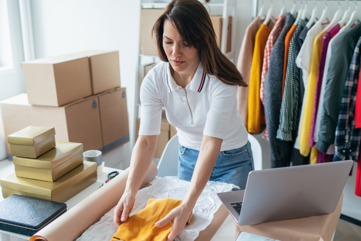 Woman packing clothing for an online business, showcasing equipment leasing and financing for growth opportunities.