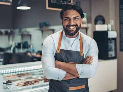Smiling business owner in a cafe, showcasing the benefits of invoice factoring for small businesses.