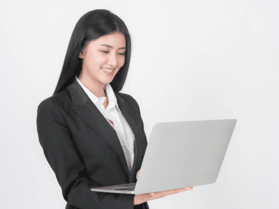 Smiling businesswoman in a suit using a laptop, representing rising confidence among small business owners.