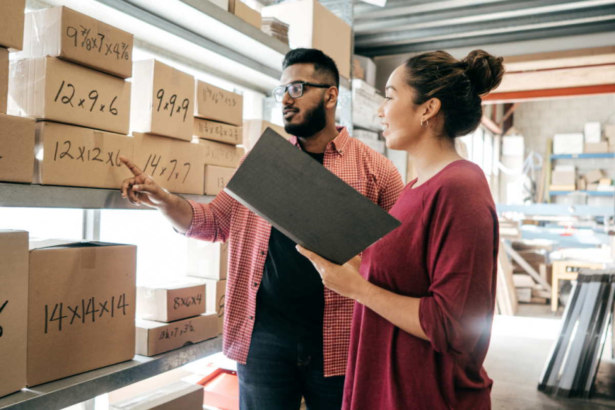 Two business professionals discussing inventory management in a warehouse, highlighting franchise growth and funding opportunities.