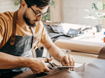 Business owner cutting leather in workshop, showcasing entrepreneurship and craftsmanship for effective financing strategies.