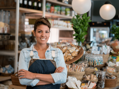 Smiling business owner in a retail store showcasing products, representing unsecured loans for business growth and sustainability.