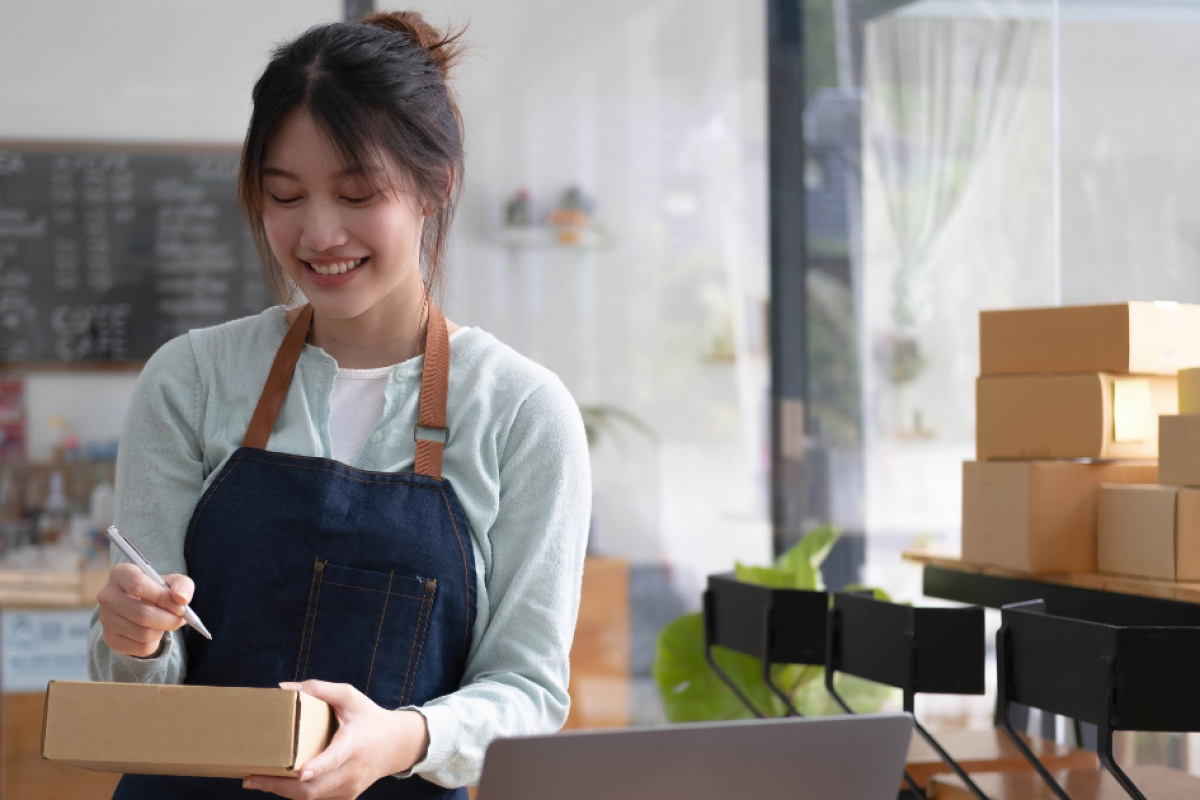 Smiling woman in an apron managing inventory in a small business, highlighting franchise opportunities and entrepreneurship.