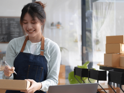 Smiling woman in an apron managing inventory in a small business, highlighting franchise opportunities and entrepreneurship.