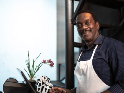 Smiling small business owner in a cafe, showcasing expert funding solutions for small business success.