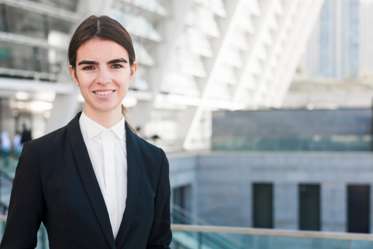 Professional woman in business attire smiling outdoors, representing small business savings strategies and financial empowerment.