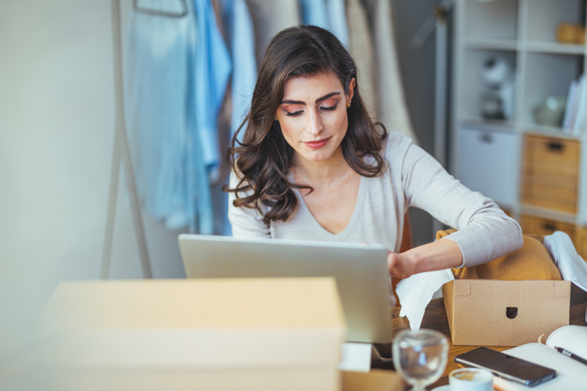 Woman working on a laptop in a cozy office, surrounded by boxes and office supplies, representing tailored medical financing solutions.