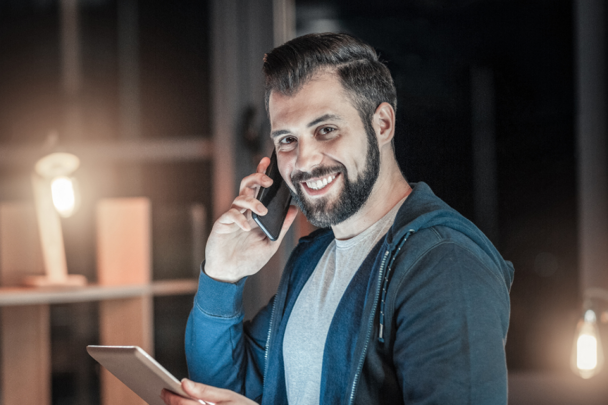 Smiling man on phone with tablet, representing effective credit building strategies without debt.